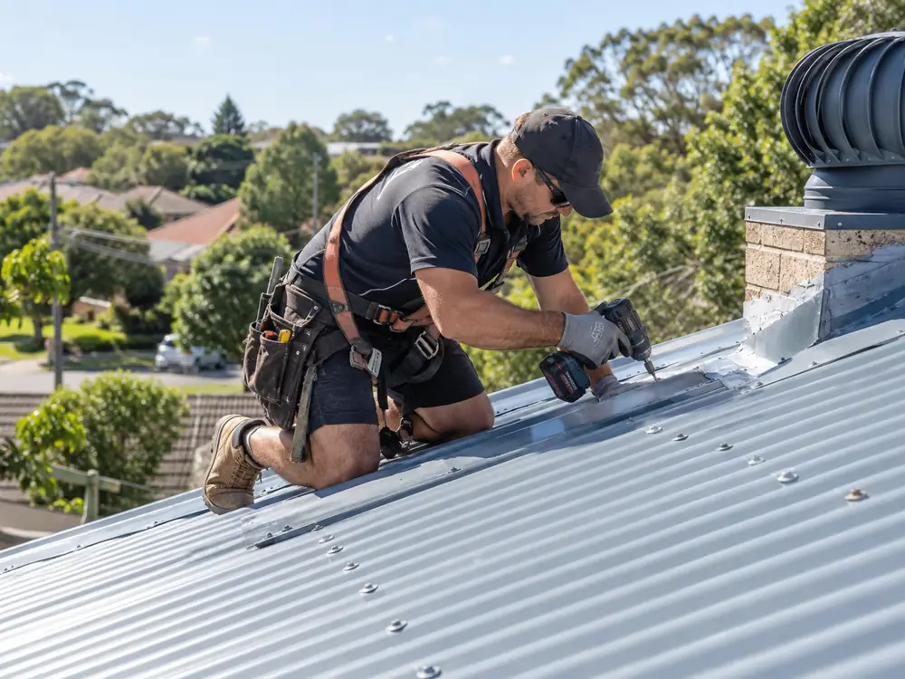 Metal roof repair worker sealing a corrugated metal roof on a suburban Sydney property