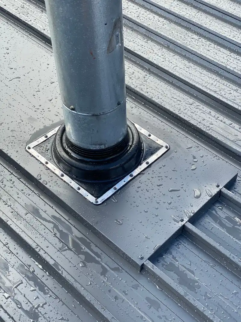 Metal roof pipe penetration with black rubber boot flashing secured to a grey metal roof in Sydney.